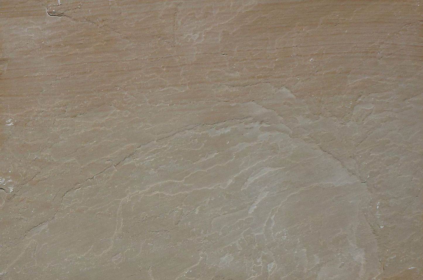 A close-up view of textured, layered brown rock with wavy, pale lines and subtle color variations. The surface appears weathered and uneven, resembling natural Buff Sandstone Paving or sandstone slabs.