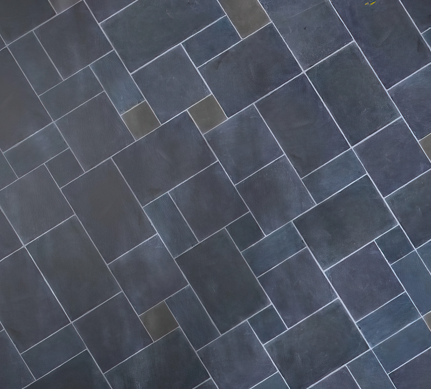A geometric pattern of rectangular paving tiles, arranged in a staggered, interlocking layout with visible white grout lines. The tiles, reminiscent of garden stepping stones, vary slightly in shade for a subtly textured appearance.