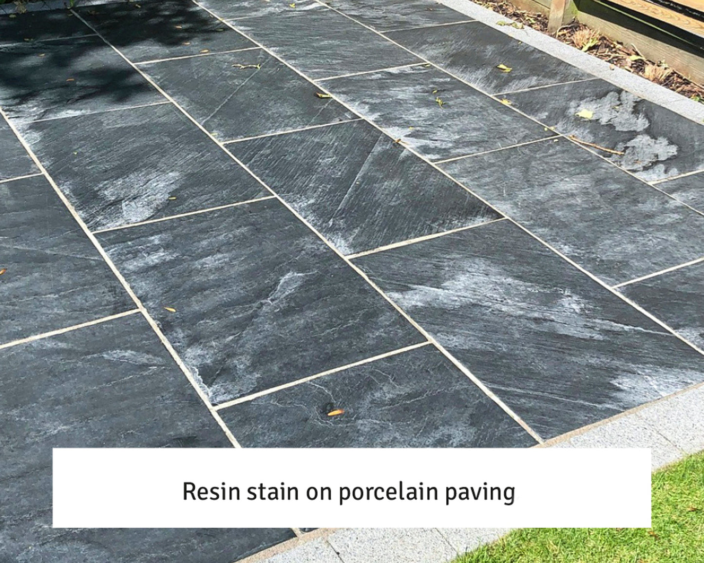 Dark porcelain paving slabs with visible streaky white resin stains across several tiles. Text overlay at the bottom reads, "Resin stain on porcelain paving." Ideal for testing an epoxy grout remover solution.