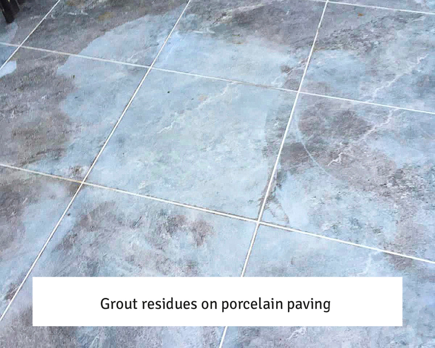 Blue-grey porcelain tiles with visible white grout residues on the surface, creating a hazy appearance across several tiles, easily treated with a suitable grout residue remover.