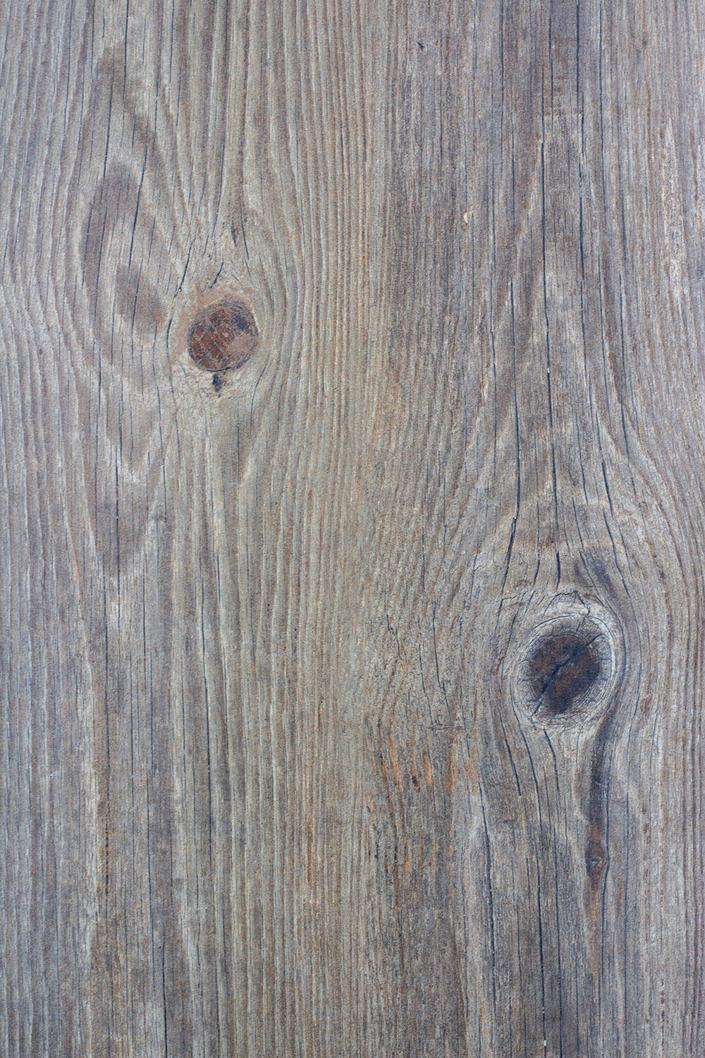 Close-up of a wood-look porcelain tile surface showing natural grain patterns and two visible knots, giving it a textured and rustic appearance in shades of brown and gray.