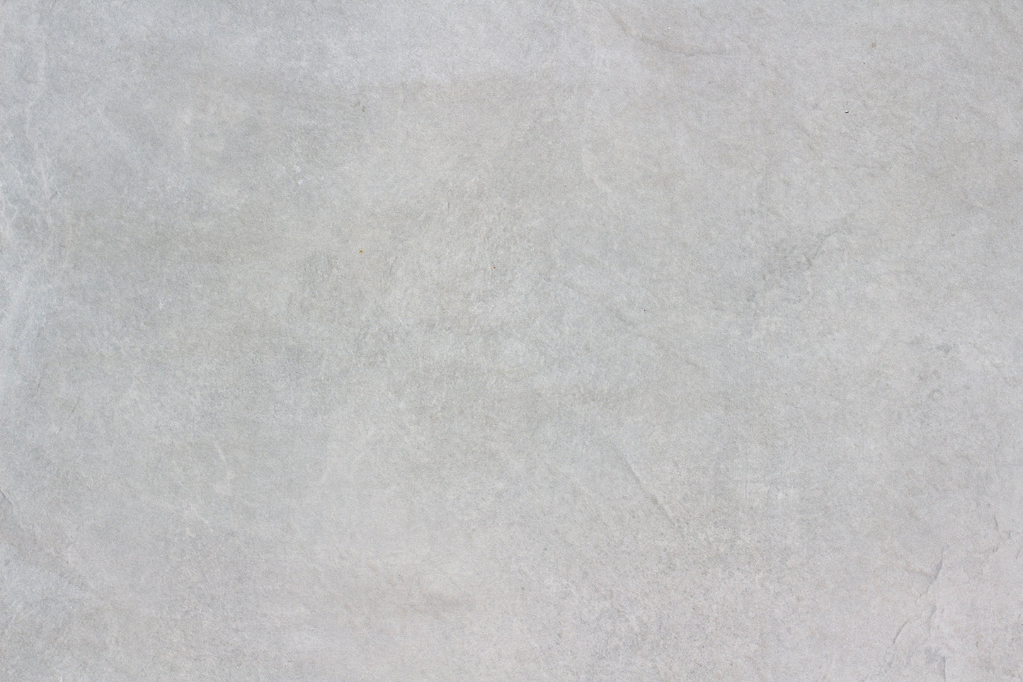 Light gray textured stone surface with subtle natural patterns and faint lines, mimicking the look of Palmer Grey Porcelain Paving Slabs and creating a neutral, minimalistic background ideal for outdoor porcelain tiles.