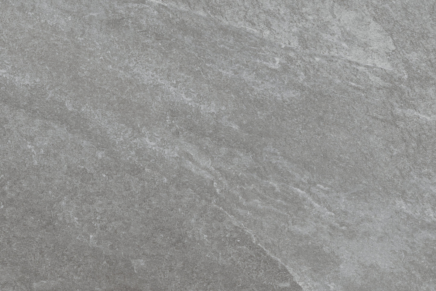 Gray stone surface with subtle natural texture and light veining, creating a slightly rough, matte appearance. Rasa Grigio Porcelain tiles offer slip-resistant paving perfect for outdoor spaces, with blended shades of lighter and darker gray.