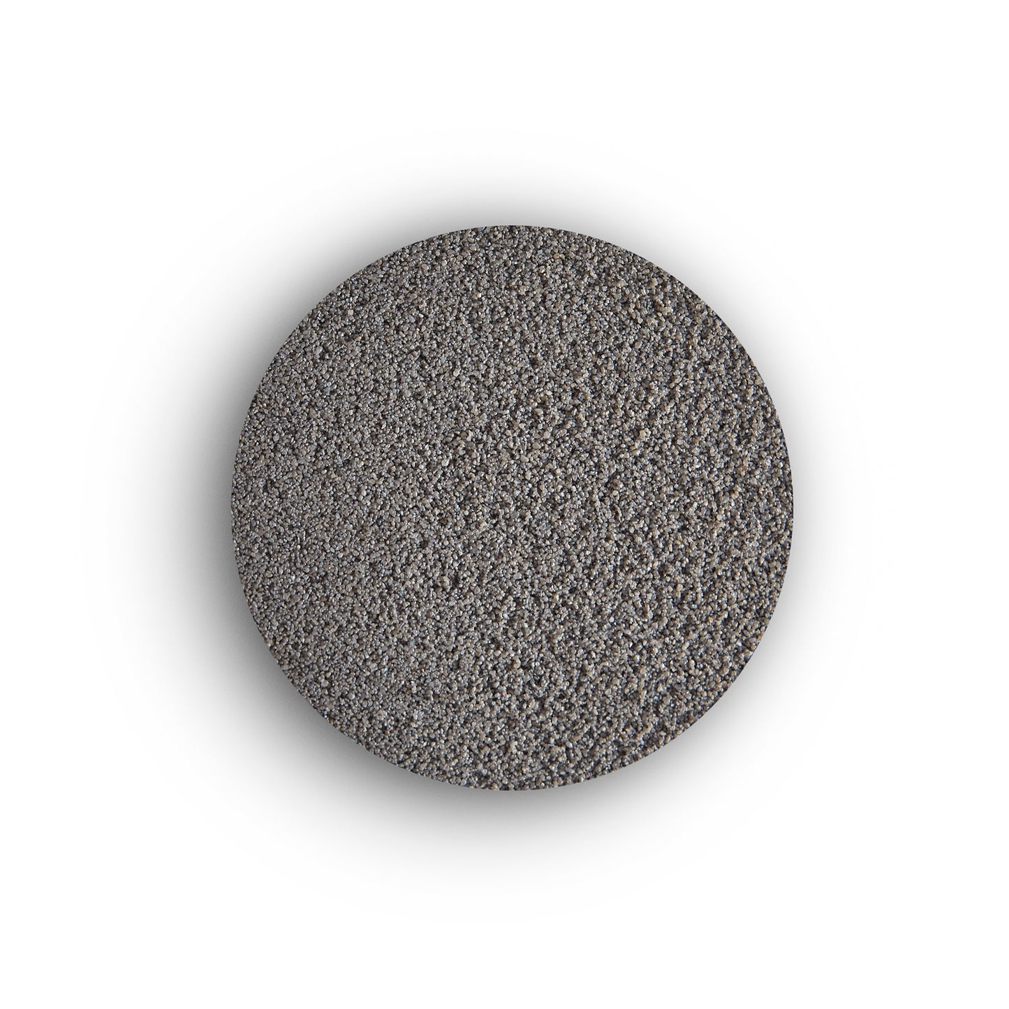 A circular mound of fine, gray granular material is centered on a white background, resembling sand or the texture of brush-in jointing solution used for external tile grout.