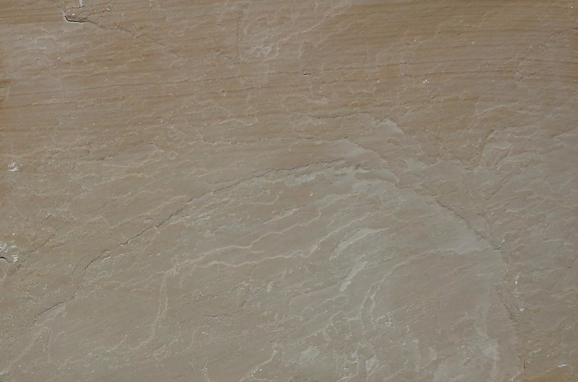 A close-up view of textured, layered brown rock with wavy, pale lines and subtle color variations. The surface appears weathered and uneven, resembling natural Buff Sandstone Paving or sandstone slabs.