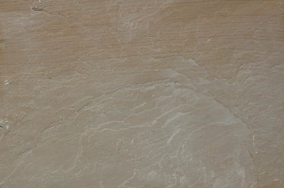 A close-up view of textured, layered brown rock with wavy, pale lines and subtle color variations. The surface appears weathered and uneven, resembling natural Buff Sandstone Paving or sandstone slabs.
