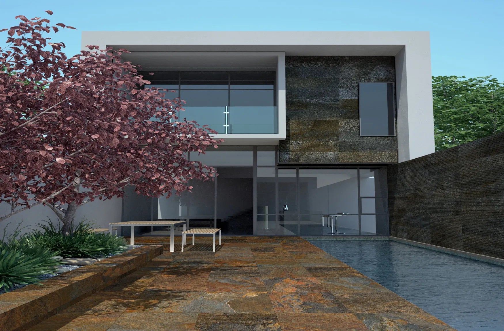 Modern two-story house with large glass windows, a patio with slip-resistant paving tiles, a pool on the right, a small table and chairs, a pink-leaved tree on the left, and greenery in the background under a clear sky.
