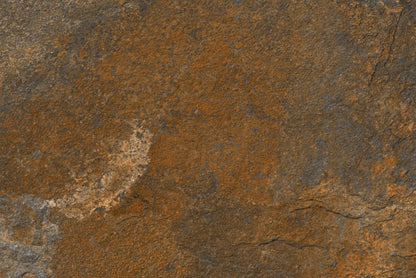 Close-up view of a rough, brown and dark gray stone surface with a textured, uneven appearance and natural color variations, reminiscent of outdoor porcelain tiles for slip-resistant paving.