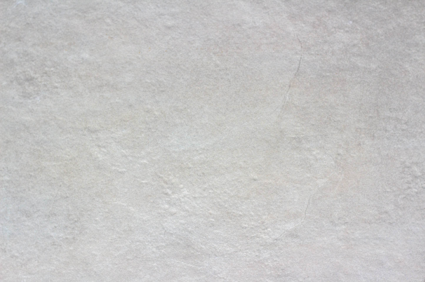 A close-up view of a light gray, slightly textured porcelain outdoor tile surface with subtle color variations and faint natural lines, ideal as a slip-resistant patio tile.
