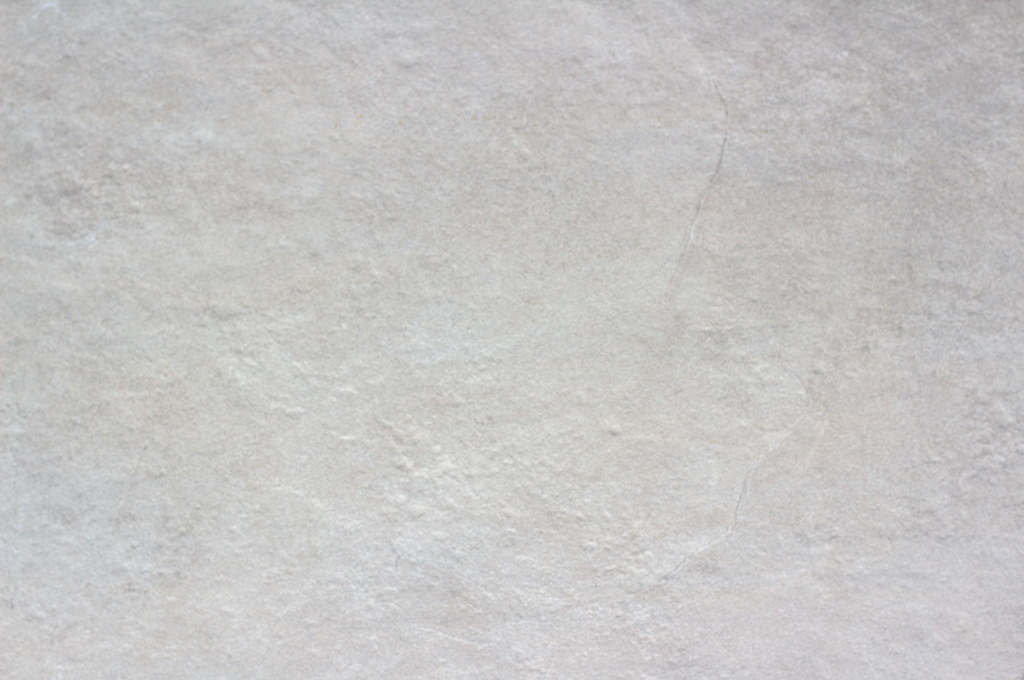 A close-up view of a light gray, slightly textured porcelain outdoor tile surface with subtle color variations and faint natural lines, ideal as a slip-resistant patio tile.
