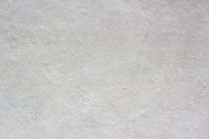 A close-up view of a light gray, slightly textured porcelain outdoor tile surface with subtle color variations and faint natural lines, ideal as a slip-resistant patio tile.