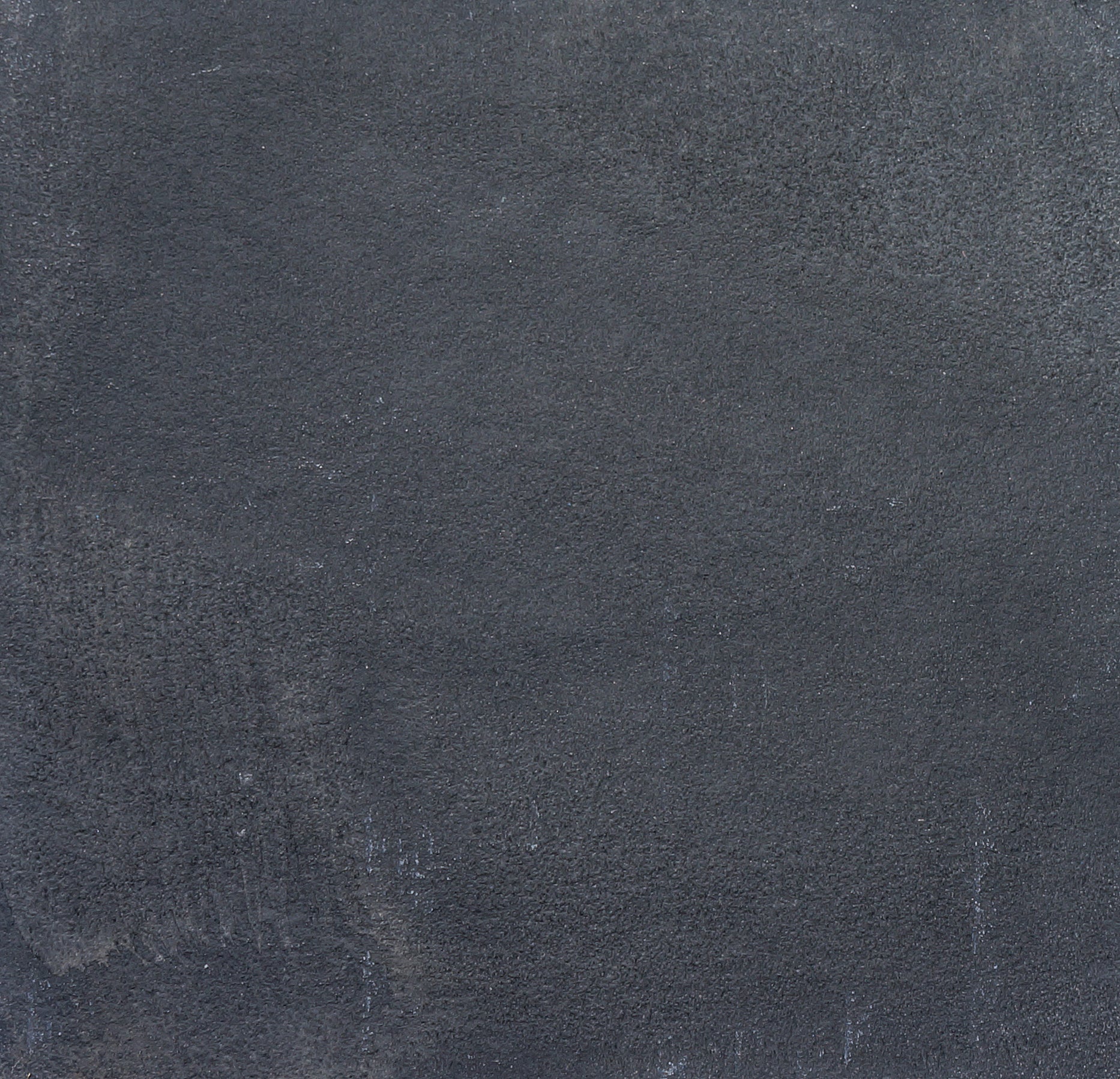 A close-up of a textured, dark gray concrete wall with subtle variations in tone and rough, uneven surface patterns, reminiscent of Kadappa Black Limestone Paving often used for stylish garden stepping stones.