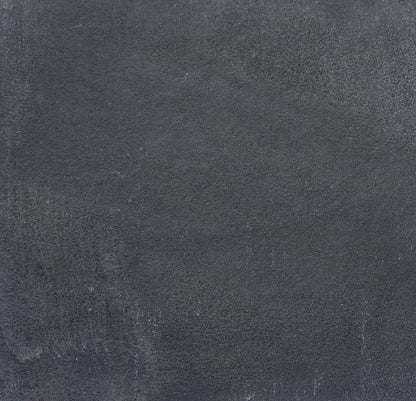 A close-up of a textured, dark gray concrete wall with subtle variations in tone and rough, uneven surface patterns, reminiscent of Kadappa Black Limestone Paving often used for stylish garden stepping stones.