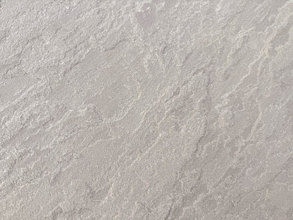 A close-up view of a textured, light grey surface with irregular, wavy patterns and subtle shading variations, resembling Kandla Grey Sandstone Paving or natural sandstone slabs.