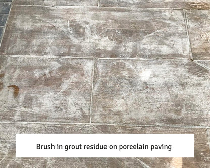Porcelain paving slabs with white grout residue streaks and patches on the surface, showing where excess grout was left after installation. Text caption at the bottom reads: "Brush in grout residue—try a sealer remover on porcelain paving.