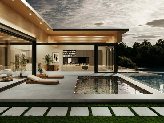 Modern house with large glass windows, a pool, and contemporary interior decor. Stylish modern tile paving surrounds the lounge chairs, set amid greenery and overlooking water with dramatic clouds filling the sky.