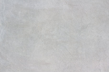 Light gray textured stone surface with subtle natural patterns and faint lines, mimicking the look of Palmer Grey Porcelain Paving Slabs and creating a neutral, minimalistic background ideal for outdoor porcelain tiles.