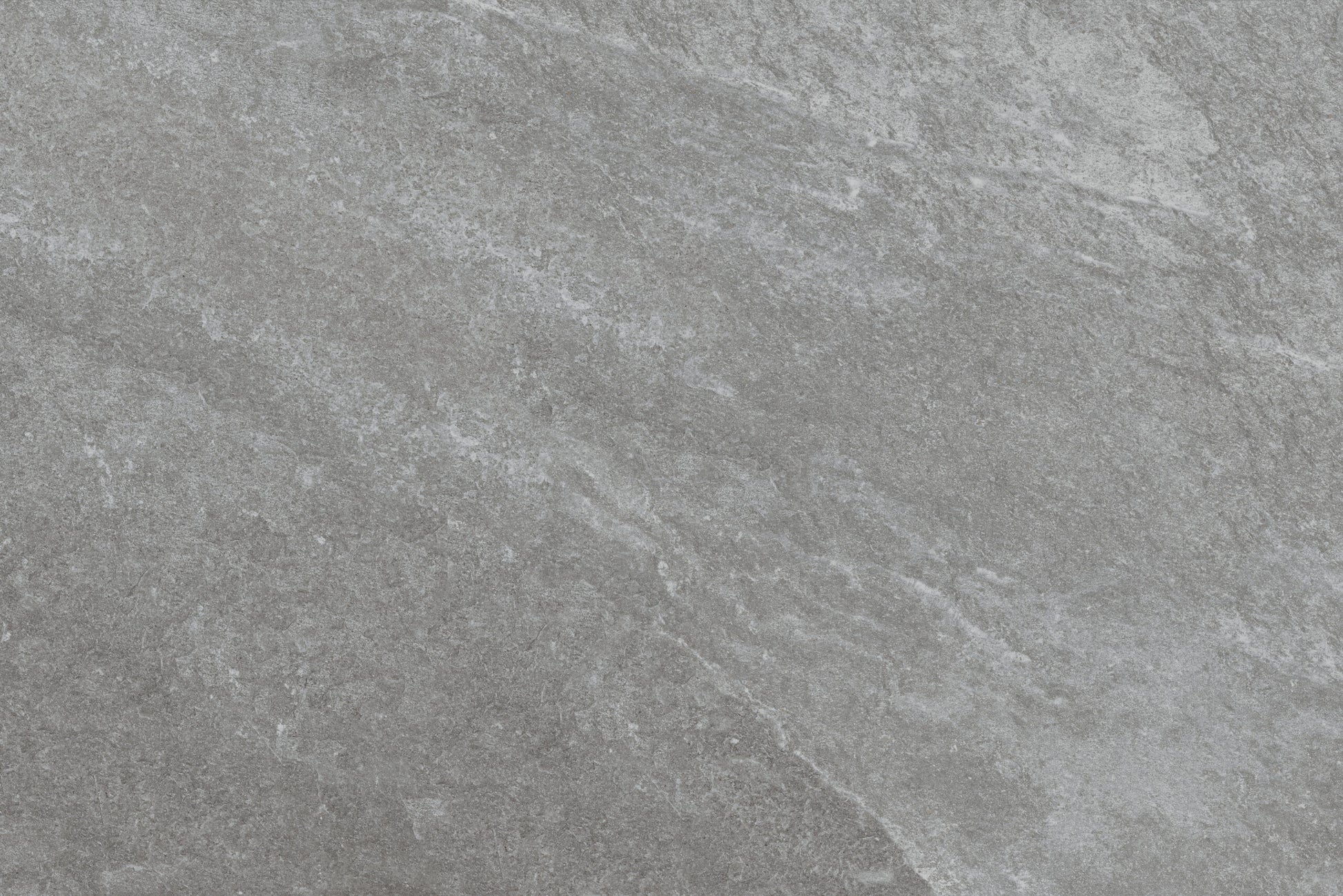 Gray stone surface with subtle natural texture and light veining, creating a slightly rough, matte appearance. Rasa Grigio Porcelain tiles offer slip-resistant paving perfect for outdoor spaces, with blended shades of lighter and darker gray.