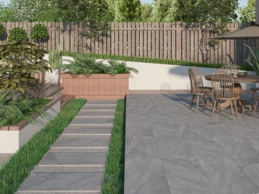 Modern backyard with a stone pathway featuring slip-resistant paving tiles leading to a raised wooden planter, lush greenery, and a patio area with dining table and chairs. A wooden fence and trees complete the serene setting.