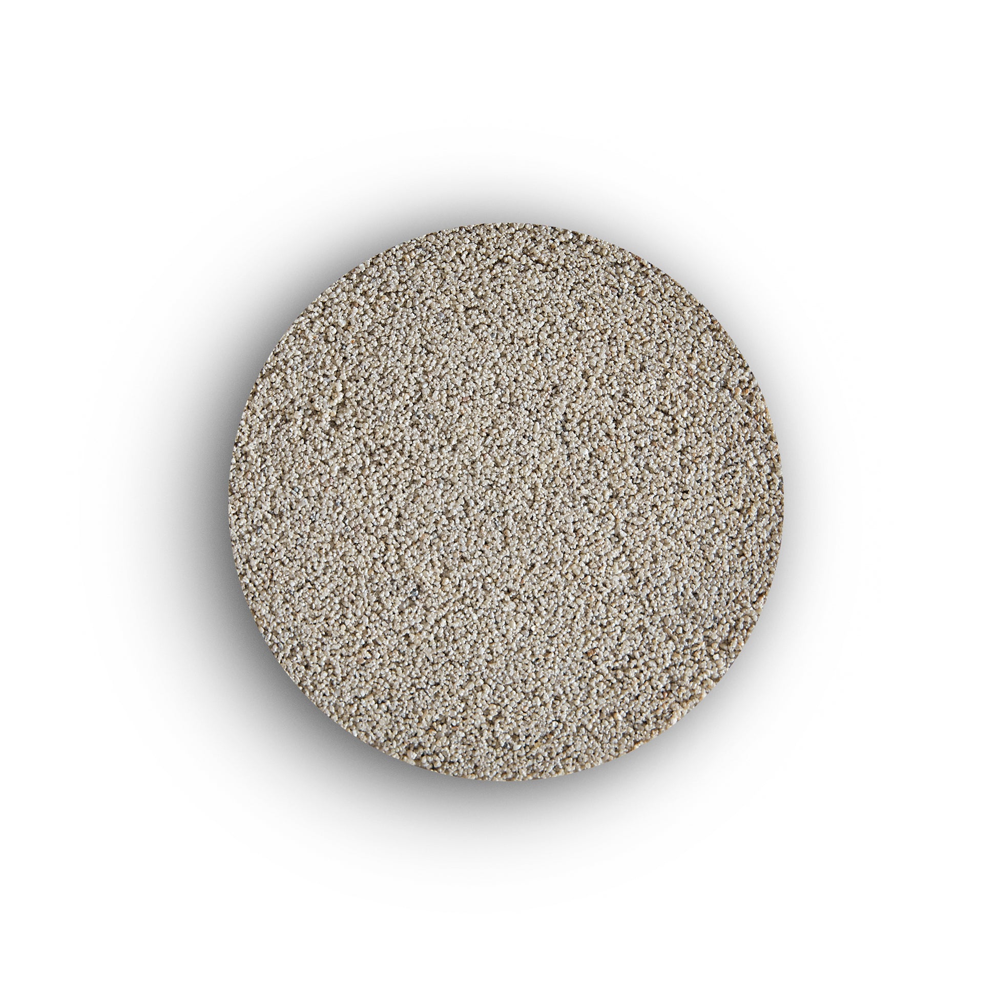 A round, flat pile of fine, light-colored sand—resembling external tile grout—is centered on a white background, casting a subtle shadow around its edges.