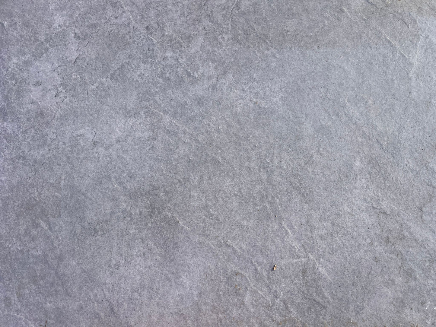 A close-up view of a smooth, gray stone surface with subtle texture and natural variations in color, reminiscent of Rasa Grigio Porcelain tiles—ideal for stylish, slip-resistant outdoor porcelain paving.