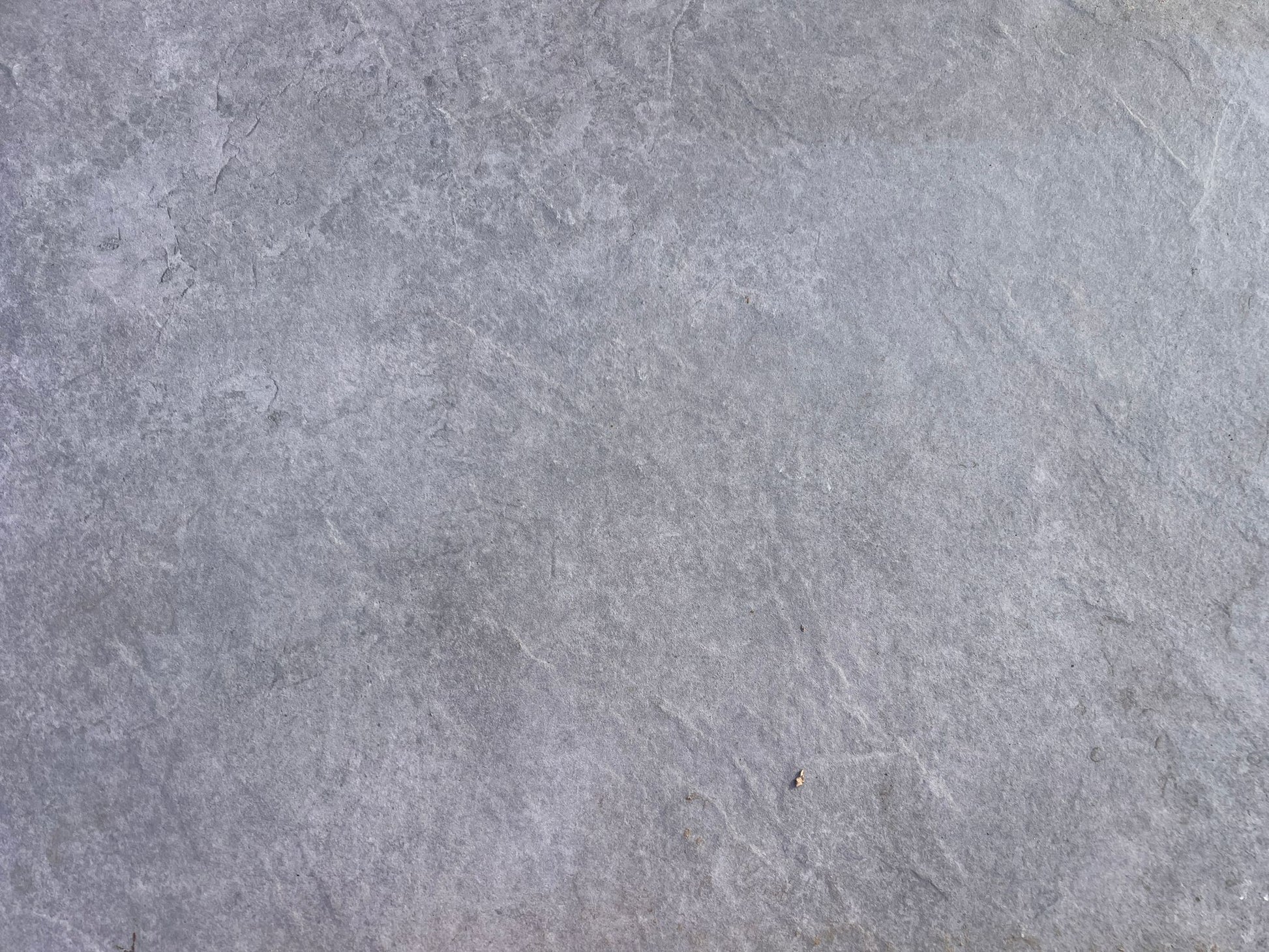A close-up view of a smooth, gray stone surface with subtle texture and natural variations in color, reminiscent of Rasa Grigio Porcelain tiles—ideal for stylish, slip-resistant outdoor porcelain paving.